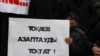 Мужчина держит плакат с надписью: «Токаев, останови пытки» — на траурном митинге в память о жертвах «кровавого января». Алматы, 13 февраля 2022 года