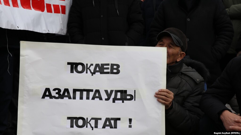 Мужчина держит плакат с надписью: «Токаев, останови пытки» — на траурном митинге в память о жертвах «кровавого января». Алматы, 13 февраля 2022 года