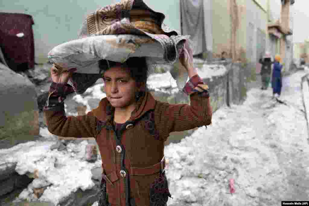 O fată cară pâine pe cap în timp ce merge pe zăpadă în Kabul, Afganistan. &nbsp;