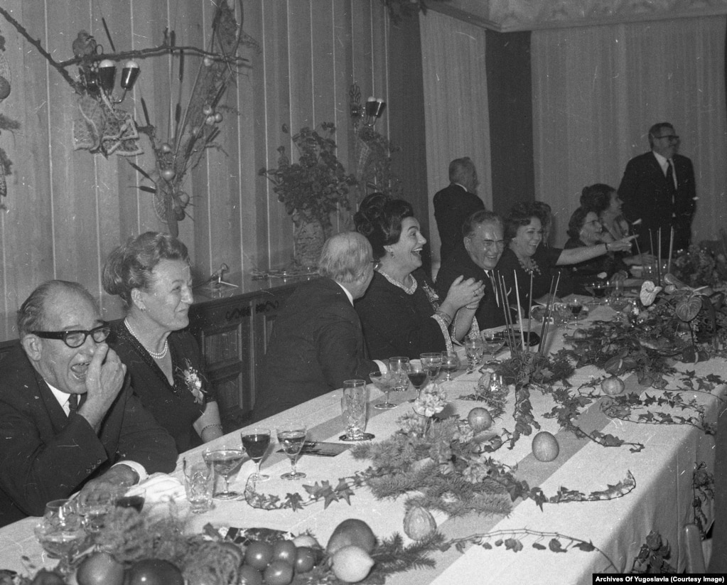 Тито с соратниками, включая его жену Йованку, смеются за праздничным ужином.