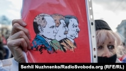Учасниця Маршу єдності з плакатом, на якому зображені Путін, Сталін і Гітлер. Київ, 12 лютого 2022 року