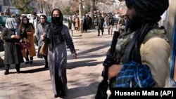 Afghan women pass a Taliban fighter on a street Kabul on February 13.