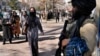 Afghan women walk past a Taliban fighter in Kabul (file photo)