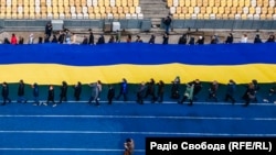 Державний прапор довжиною у двісті метрів розгорнули учасники акції у Дня єднання на стадіоні «Олімпійський» у Києві. Україна, 16 лютого 2022 року