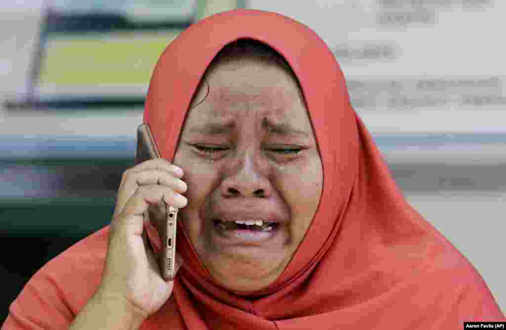 A woman cries as she uses the recovered mobile phone of her daughter, who was killed in the massive earthquake in Palu, Central Sulawesi, Indonesia. The mother did not get the chance to see the body of her daughter before she was buried earlier in a mass grave. (AP/Aaron Favila)