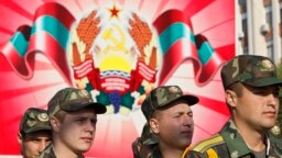 Войници от самообявилата се Приднестровска молдовска република (ПМР) по време военен парад в Тираспол през 2012 г. Зад тях е гербът на ПМР.