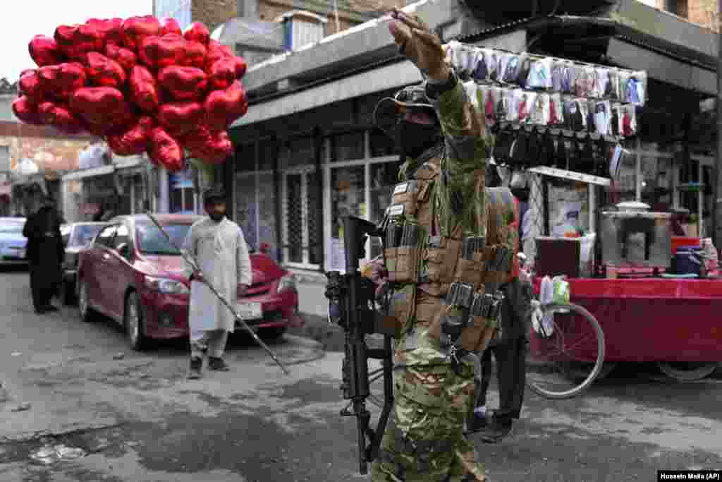 Talibanski borac upravlja saobraćajem dok ulični prodavač prodaje crvene balone u obliku srca na Dan zaljubljenih u Kabulu, Afganistan, 14. februar.