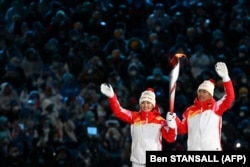 Chinese athletes Dinigar Ilhamjan (left) and Zhao Jiawen hold the Olympic flame during the opening ceremony of the Winter Olympics on February 4. “This is propaganda. There’s no other way to describe it,” Badiucao says.