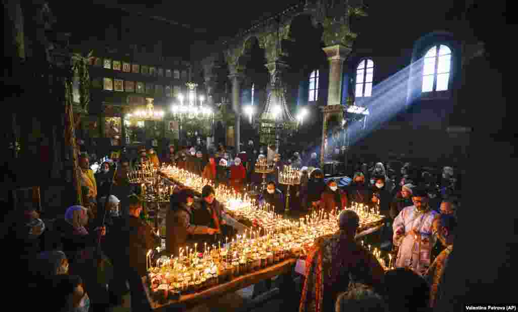 Priests read prayers in honor of St. Haralampus as believers gather around candles stuck to jars of honey arranged in a cross during a mass for the &quot;sanctification of honey&quot; at the Presentation of the Blessed Virgin church in the town of Blagoevgrad, south of the Bulgarian capital, Sofia. Despite the COVID-19 pandemic, the Bulgarian Orthodox Church marked the day of St. Haralampus, the Orthodox patron saint of beekeepers, by performing a ritual for health and a rich harvest.