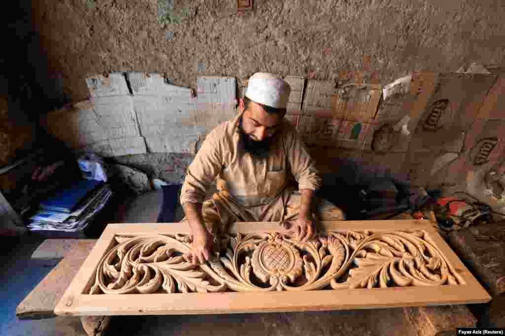 Un dulgher pakistanez șlefuiește o sculptură în panouri într-un atelier din Peshawar.&nbsp;
