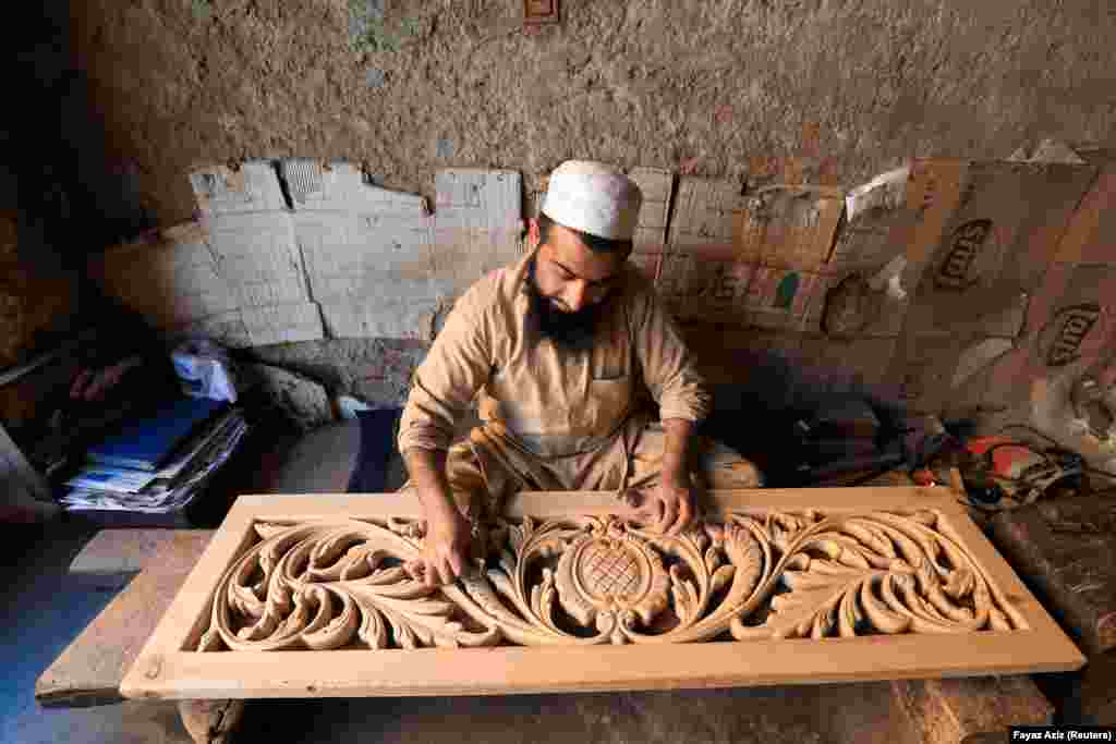 A Pakistani carpenter sands a panel-carving at a workshop in Peshawar.&nbsp;