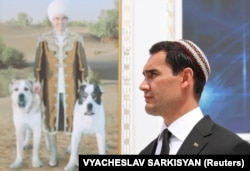 Turkmen President Serdar Berdymukhammedov in front of a portrait of his father, former President Gurbanguly Berdymukhammedov