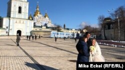 Një çift i sapomartuar në sheshin pranë një katedraleje në Kiev më 12 shkurt, 2022. Pavarësisht kërcënimit të një lufte të re me Rusinë, jeta vazhdon normalisht në kryeqytetin e Ukrainës. 