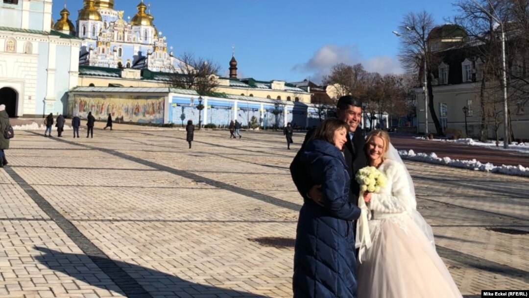 Нова брачна двојка позира на плоштадот пред киевската катедрала Свети Михаил, 12 февруари 2022 година. 
