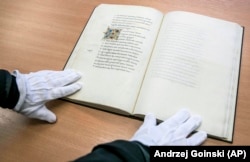 A gloved librarian displays the manuscript.