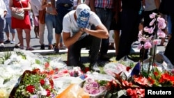 Fransiýanyň Nise şäherindäki hüjümiň bolan ýerinde adamlar gül goýýar. 15-nji iýul, 2016 ý.