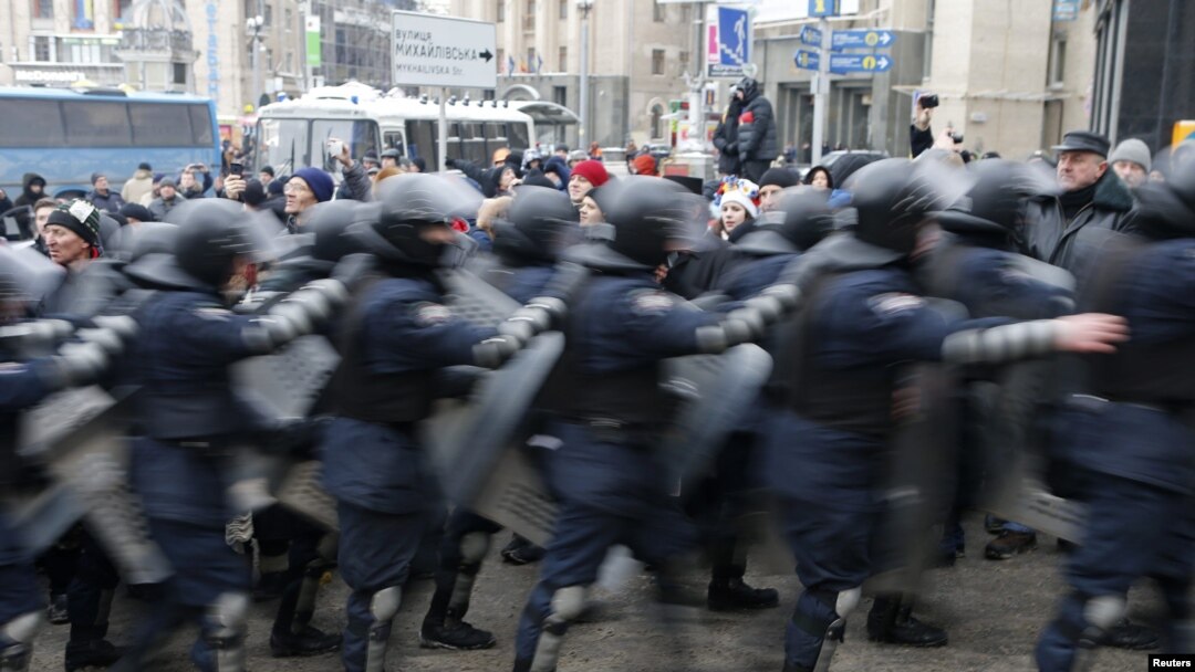 A line of Ukranian riot police moves past protesters in Independence Square in Kyiv.