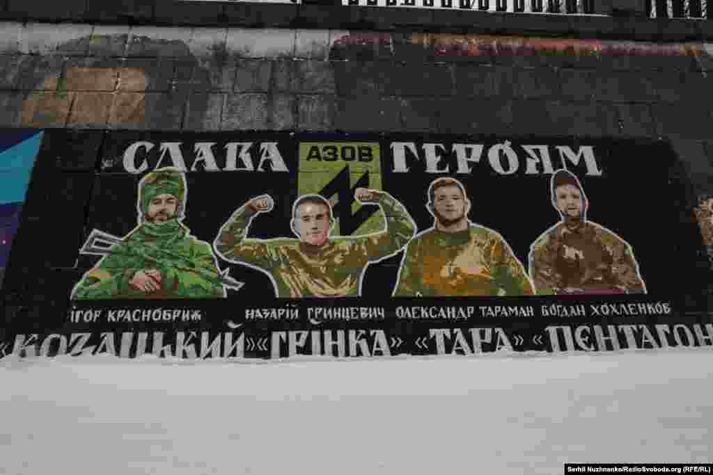 Біля Пішохідного мосту у Києві, в районі Поштової площі, є чимало муралів, створених у пам'ять загиблих українських військових. І кожен має свою історію.Один із муралів присвячений полеглим бійцям полку «Азов». «Цей мурал вшановує пам'ять хоробрих захисників, які віддали своє життя за свободу та незалежність України», – зазначають волонтери, які долучились до створення цього муралу.На ньому зображені четверо українських військових, які загинули під час російсько-української війни. Ігор «Козацький» Краснобриж і Богдан «Пєнтагон» Хохленков загинули в боях за Маріуполь. Олександр «Тара» Тараман поліг навесні 2022 року підчас оточення Маріуполя. Назарій «Грінка» Гринцевич загинув 6 травня 2024 року в Серебрянському лісі на Луганщині
