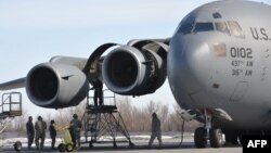 U.S. servicemen perform their daily routines by a 437th Air Wing C-17 military transport plane on the runway at the transit center in Manas, Kyrgyzstan.