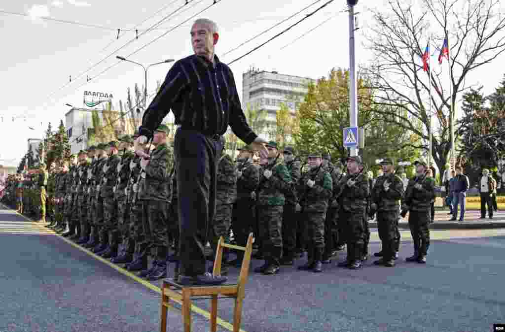 A man stands on a chair as separatist rebels stand in line during a rehearsal for a military parade in downtown Donetsk in eastern Ukraine. (epa/Alexander Ermochenko)