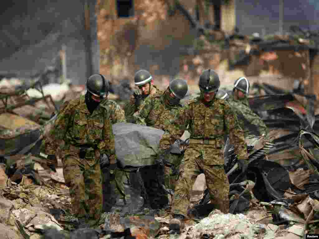 Rescue workers carry the body of a tsunami victim in the town of Otsuchi on March 11