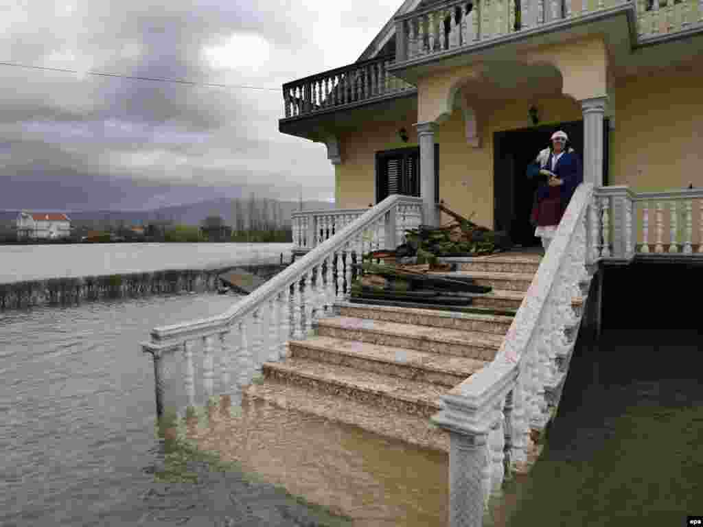 A woman looks at floodwaters outside her house in Obot, Albania. - Albanian authorities have declared a natural disaster in several northwestern regions of the country, where flooding has forced the evacuation of hundreds of people. Photo by epa