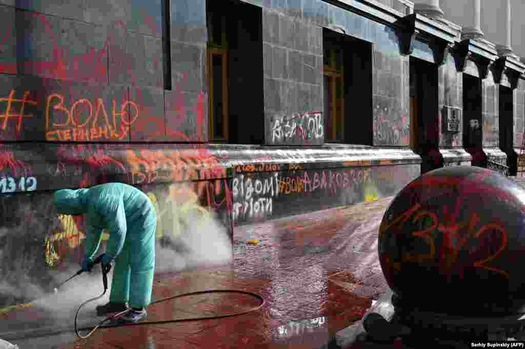 A cleaner washes away inscriptions left by protesters on the Ukrainian president&#39;s office in Kyiv during a recent rally demanding the release of Serhiy Sternenko, a civil activist and former leader of the far-right group Right Sector. (AFP/Serhiy Supinsky)