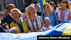 Президентка Єврокомісії Урсула фон дер Ляєн (ліворуч) долучилася до розгортання велетенського українського прапора на масовій акції в Брюсселі у День Незалежності України