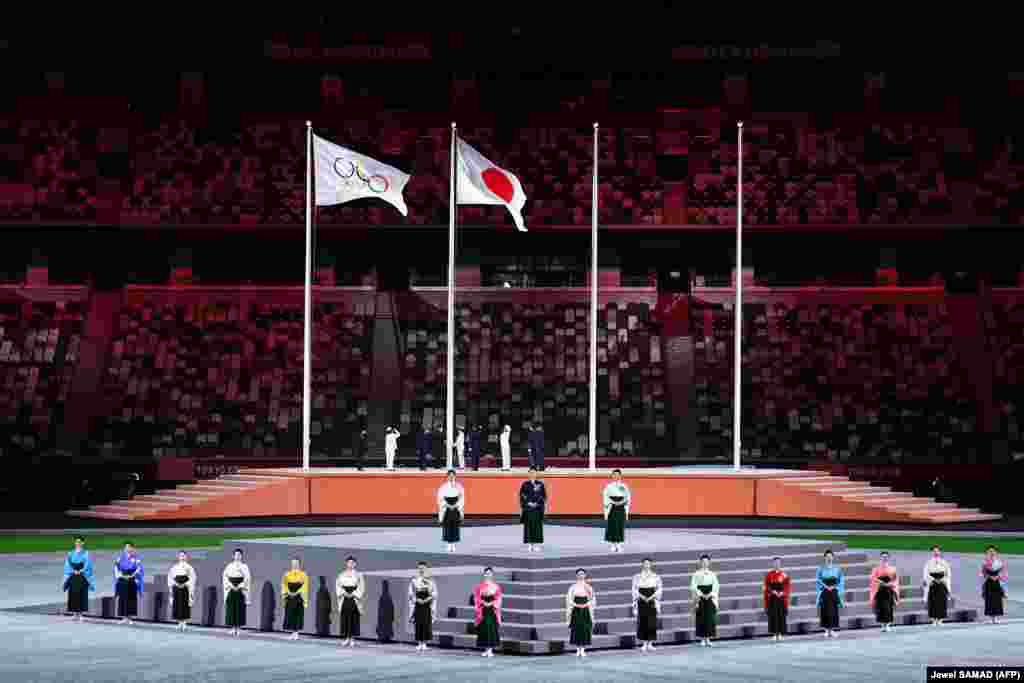 Performers sing the Japanese national anthem as the Olympic flag and Japan&#39;s flag are raised during the closing ceremony of the Tokyo 2020 Olympic Games, at the Olympic Stadium, in Tokyo, on August 8, 2021.