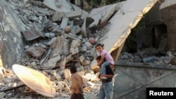 Children walk along a damaged street filled with debris in the Damascus suburb of Zamalka on October 3. 