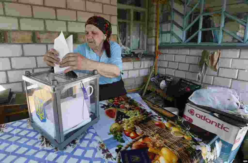 An elderly woman casts her vote at a mobile polling station, outside her home outside Kyiv.