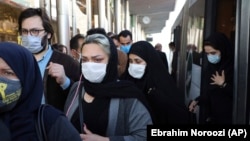 Маска таққан адамдар қоғамдық көліктен шығып барады. Тегеран, қазан айы 2020 жыл.