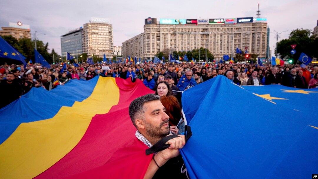 Учасники акції тримають великі прапори Румунії та Євроcоюзу під час мітингу напередодні переголосування президентських виборів у Бухаресті, Румунія, 9 травня 2025 року