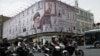FILE PHOTO: People ride motorcycles near a billboard with an image of the late Iranian Supreme Leader Ayatollah Ali Khamenei, in Tehran