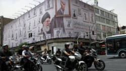 People in Tehran ride motorcycles on May 19 near a billboard with an image of the late Iranian Supreme Leader Ayatollah Ali Khamenei. 
