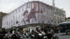 People ride motorcycles near a Tehran billboard with an image of Iran's late supreme leader, Ayatollah Ali Khamenei. 
