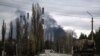 Ukraine - A military vehicle drives on a road as smoke rises from a power plant after shelling outside the town of Schastia, near the city of Lugansk, February 22, 2022.