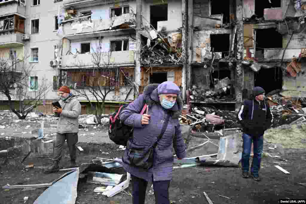 A woman walks in front of a damaged residential building in Kyiv, where a military shell is thought to have hit on February 25.
