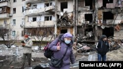 Жена со ранец оди пред оштетена станбена зграда предградие на Киев 