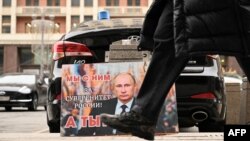 „Vele vagyunk Oroszország szuverenitásáért! És ti?” – olvasható a Vlagyimir Putyin orosz elnököt ábrázoló plakáton az orosz Állami Duma épülete előtt Moszkvában 2022. február 24-én