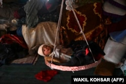 An Afghan internally displaced toddler rests in a hammock inside at temporary mud house at the Shaidayee refugee camp in Herat Province.