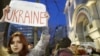Učesnica protesta nosi transparent sa porukom "Stojimo sa Ukrajinom" 