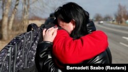 La un punct de trecere a frontierei dintre Ungaria și Ucraina, o femeie își îmbrățișează fiul. ONU estimează că mii de ucraineni au părăsit deja țara din fața războiului ordonat de președintele Rusiei, Vladimir Putin.