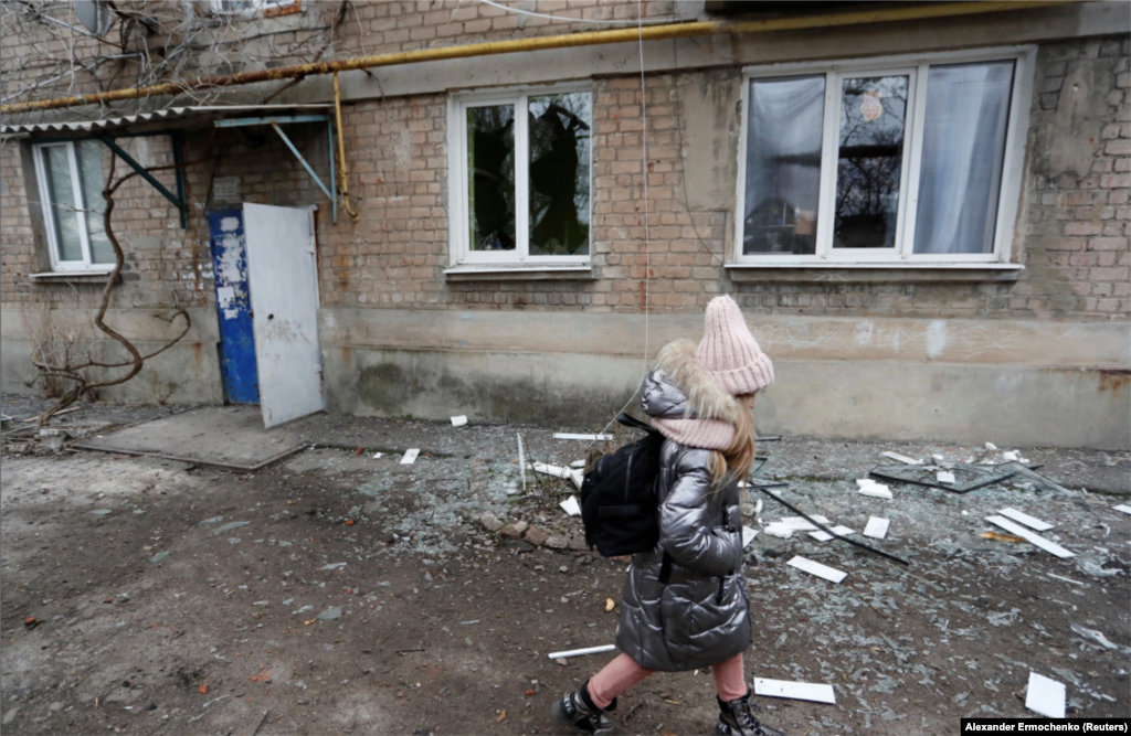 В оккупированном городе Ясиноватая на Донбассе девочка проходит мимо жилого дома, который, по словам местных жителей, пострадал в результате недавних обстрелов