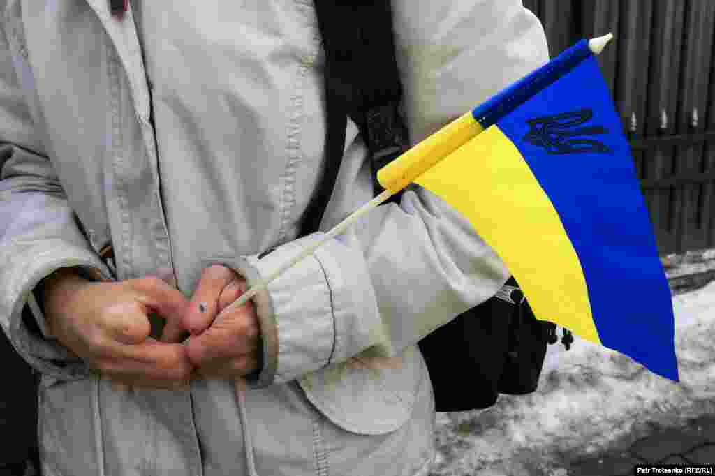 Акцияға қатысушы адам Украина туын бейнелейтін жалауша ұстап тұр.
