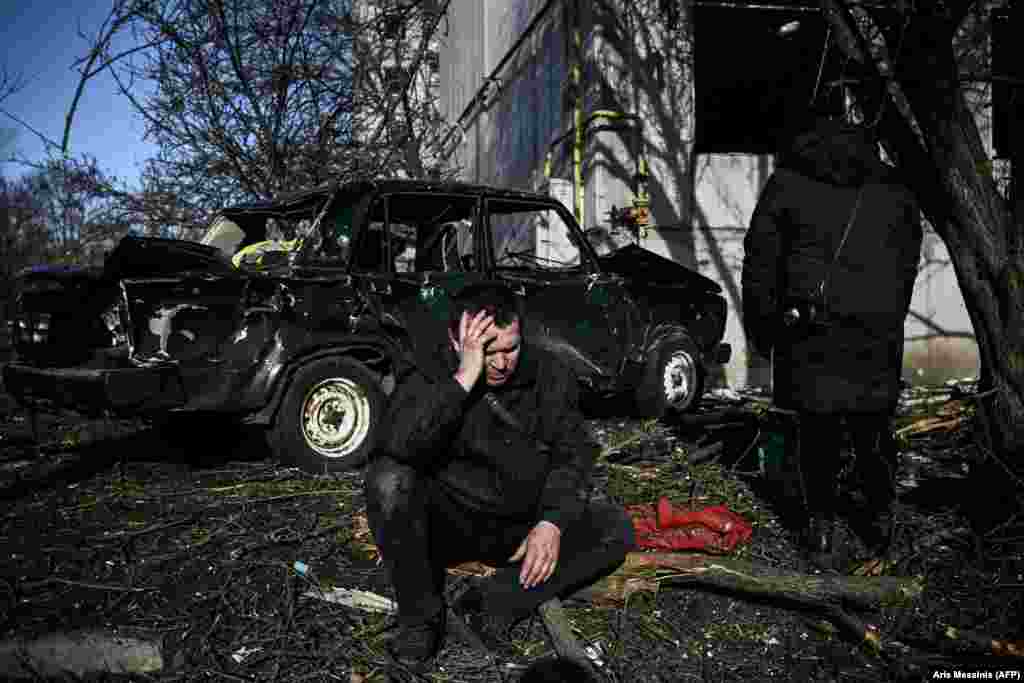 Мужчына сядзіць ля свайго разбуранага дому пасьля выбуху ў горадзе Чугуеве на ўсходзе Украіны. 24 лютага