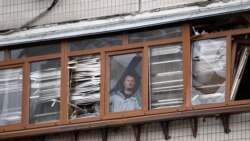 Muškarac gleda sa balkona oštećene stambene zgrade u ulici Košica, 25. februara 2022.