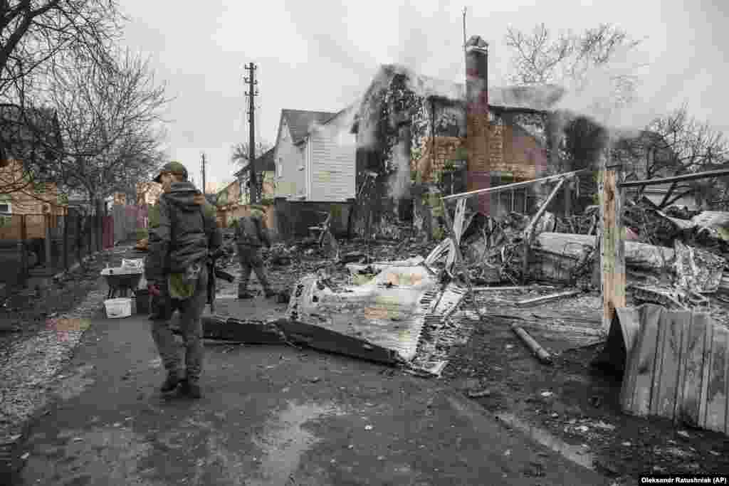 Militari ucraineni merg spre rămășițele unui aparat de zbor prăbușit în Kiev. 25 februarie 2022