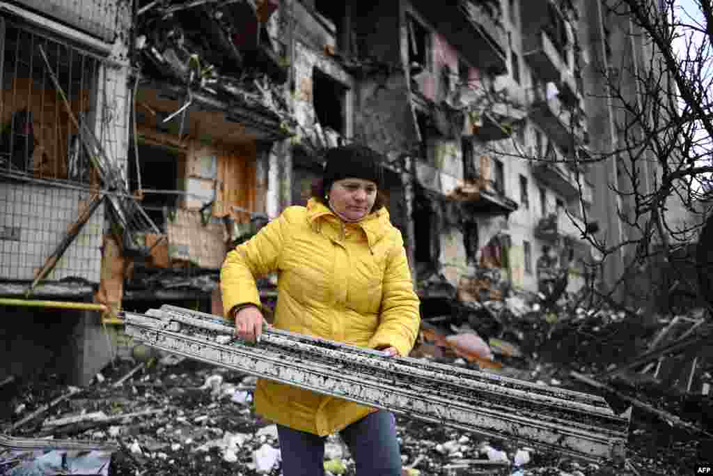 Február 25-én kora reggel robbanások hallatszottak Kijevben, miközben megszólaltak a légi szirénák. Az orosz erők péntek hajnalban érték el Kijev külvárosát, ahol ez a nő is él. Most saját kezével próbálja meg eltakarítani a keletkezett törmeléket