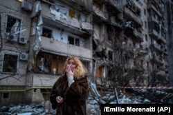 A woman reacts next to her house following a Russian rocket attack on the capital, Kyiv, on February 25, 2022.